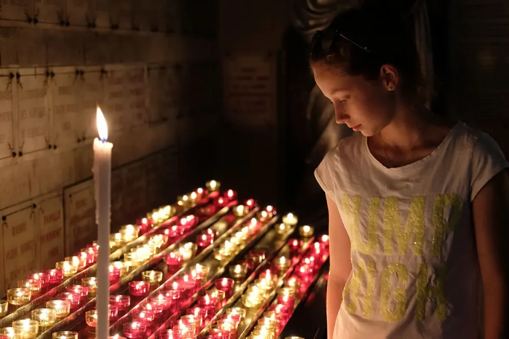 Jeune fille illuminée par les bougies dans la crypte de Notre-Dame de la Garde lors d'une journée à Marseille.