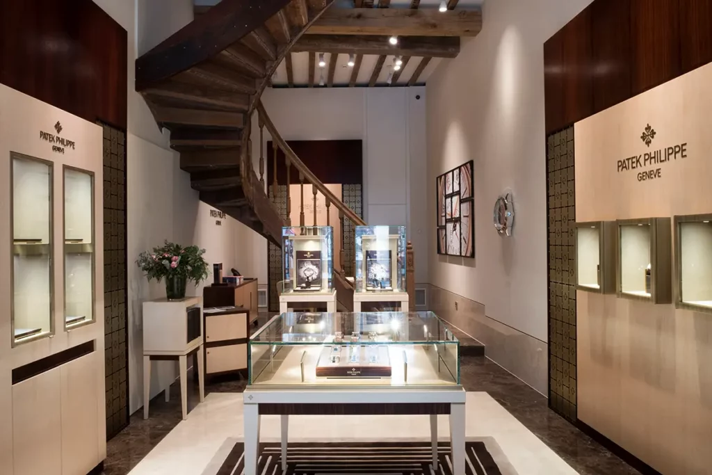 Intérieur de la boutique Patek Philippe chez la Maison De Greef à Bruxelles avec l'escalier en bois du XVe siècle et les vitrines de montres.