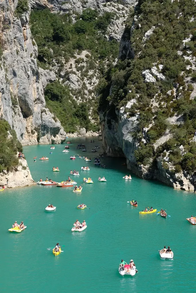 Gros plan vertical sur les embarcations de vacanciers s'engouffrant entre les hautes falaises des Gorges du Verdon.