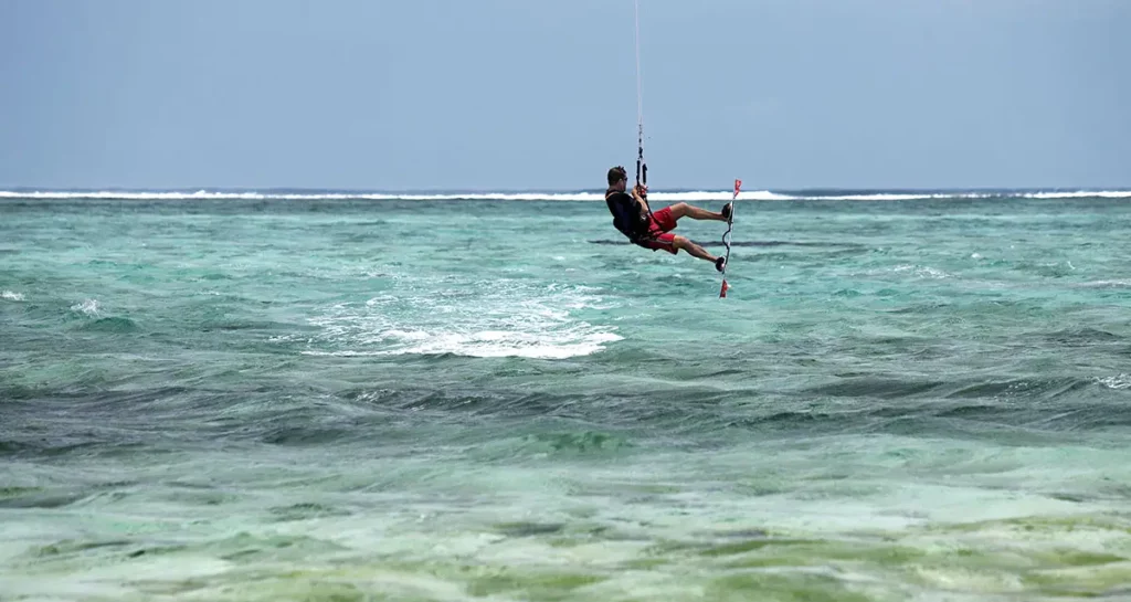 Un homme pratiquant le kitesurf sur les eaux turquoise du lagon du So Sofitel Mauritius, à proximité du spot du Morne.