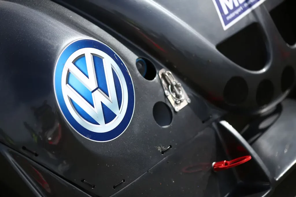 Gros plan sur le logo VW intégré dans l'optique de phare d'une Volkswagen Fun Cup grise.