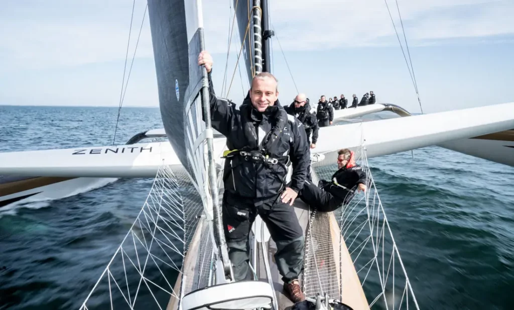 Le blogueur belge Michel Gronemberger à l'avant du trimaran Spindrift 2, avec la coque centrale et les flotteurs s'étendant derrière lui.