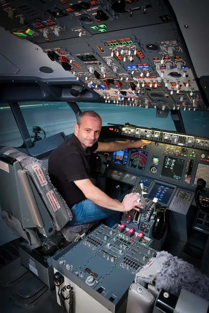 Portrait vertical de Michel Gronemberger aux commandes du simulateur Boeing 737-800 à l'European Flight Simulator.