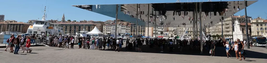 Photo panoramique de l'ombrière avec toiture en miroir sur le quai du Vieux-Port lors d'une journée à Marseille.