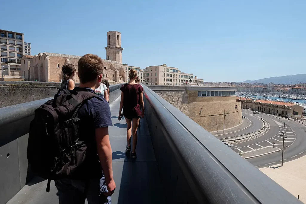 Groupe de visiteurs traversant la passerelle du Fort Saint-Jean vers le Panier lors d'une journée à Marseille.