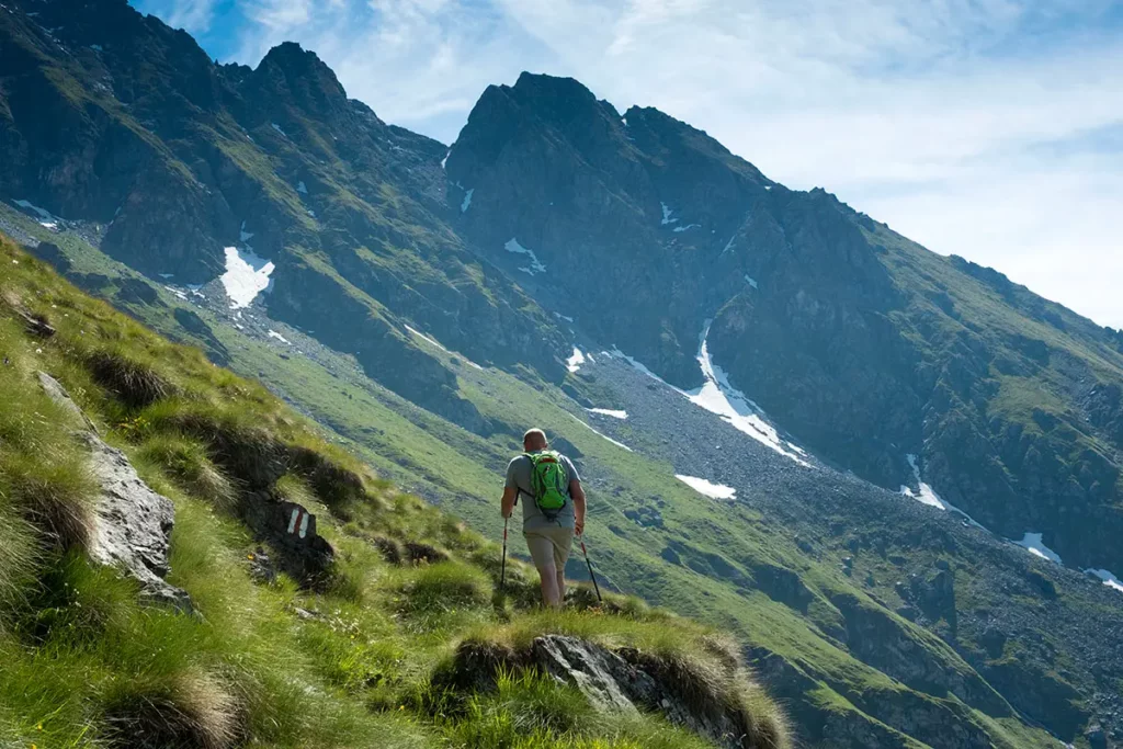 Photo en contre-plongée d'un randonneur montant le Sentier des Chamois vers le Col de Louvie à Verbier.