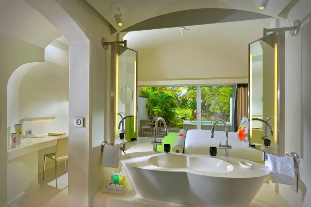 Vue depuis la salle de bain d'une SO Suite au So Sofitel Mauritius avec vasques modernes, lit King Size et vue sur le jardin privé.