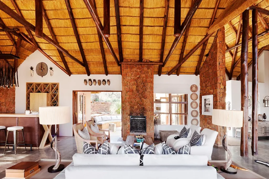 Salon et bar du Esiweni Luxury Safari Lodge avec murs en pierre naturelle et décoration africaine raffinée.