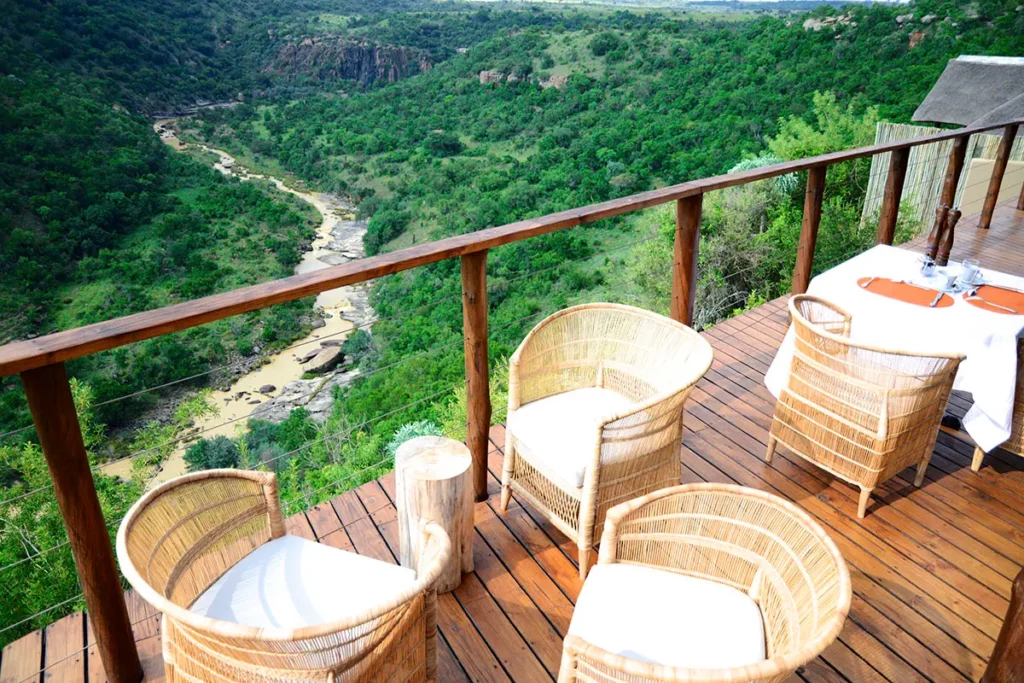 Table dressée pour le dîner sur la terrasse du Esiweni Luxury Safari Lodge avec vue sur la rivière asséchée.