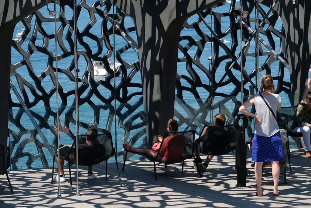 Visiteurs se relaxant sur la terrasse du MuCEM face à la Méditerranée lors d'une journée à Marseille.