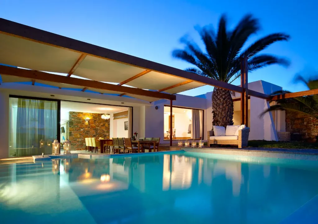 Villa Club du St. Nicolas Bay Resort Hotel & Villas à l'heure bleue, avec piscine éclairée et lumières chaleureuses de l'intérieur.