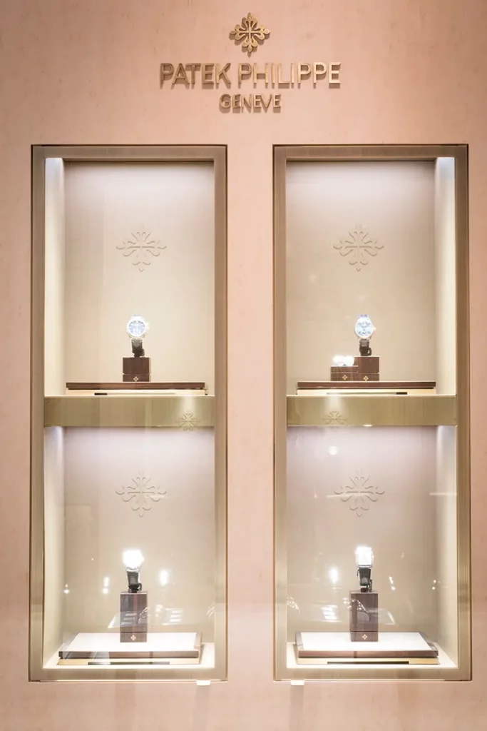 Vitrine murale avec quatre montres de luxe sous le logo Patek Philippe Genève à la Maison De Greef.