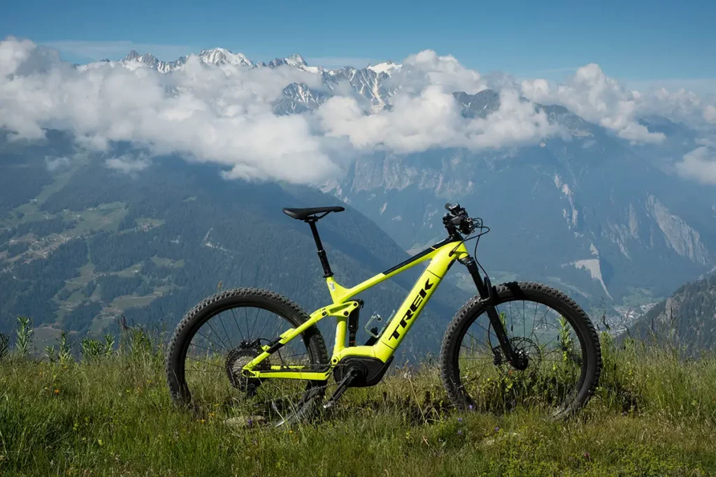 VTT électrique Trek Powerfly 2018 jaune fluo posé en montagne avec panorama sur les Alpes à Verbier en été.