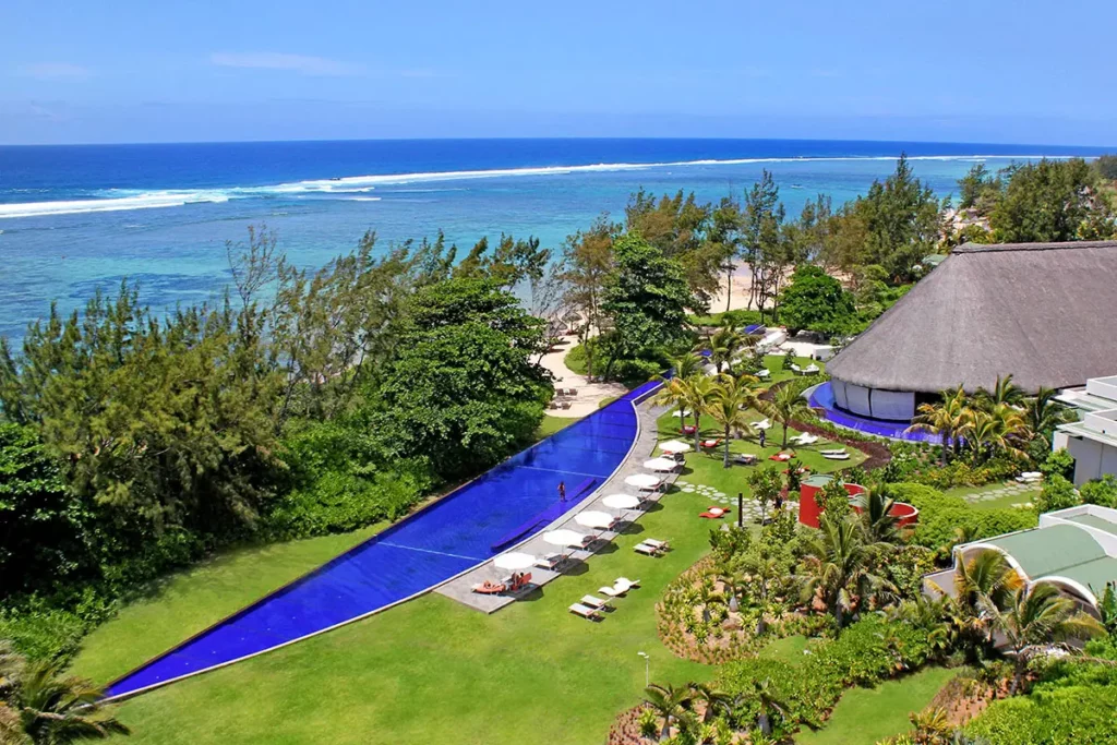 Vue aérienne du So Sofitel Mauritius montrant le toit de chaume du restaurant Le Flamboyant et la piscine en forme de machette face à l'océan Indien.