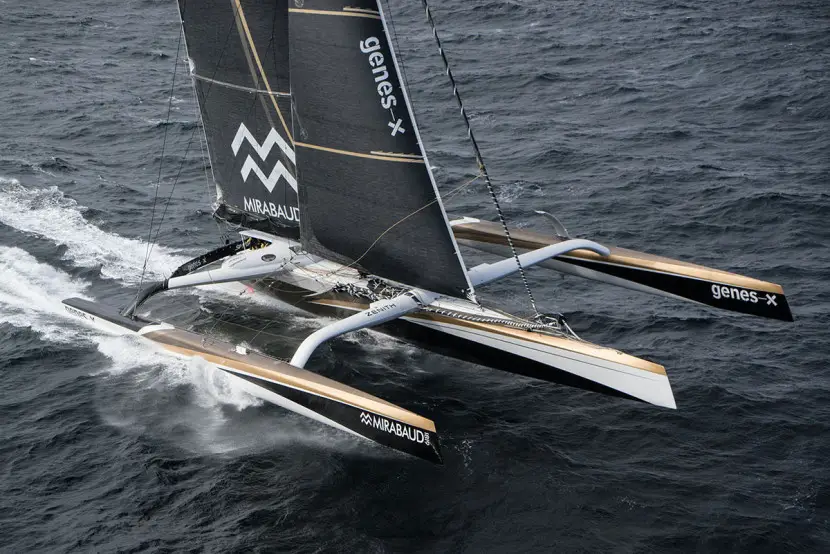 Vue aérienne du maxi-trimaran Spindrift 2 (Sails of Change) naviguant à pleine vitesse sur l'océan, prise depuis un hélicoptère.