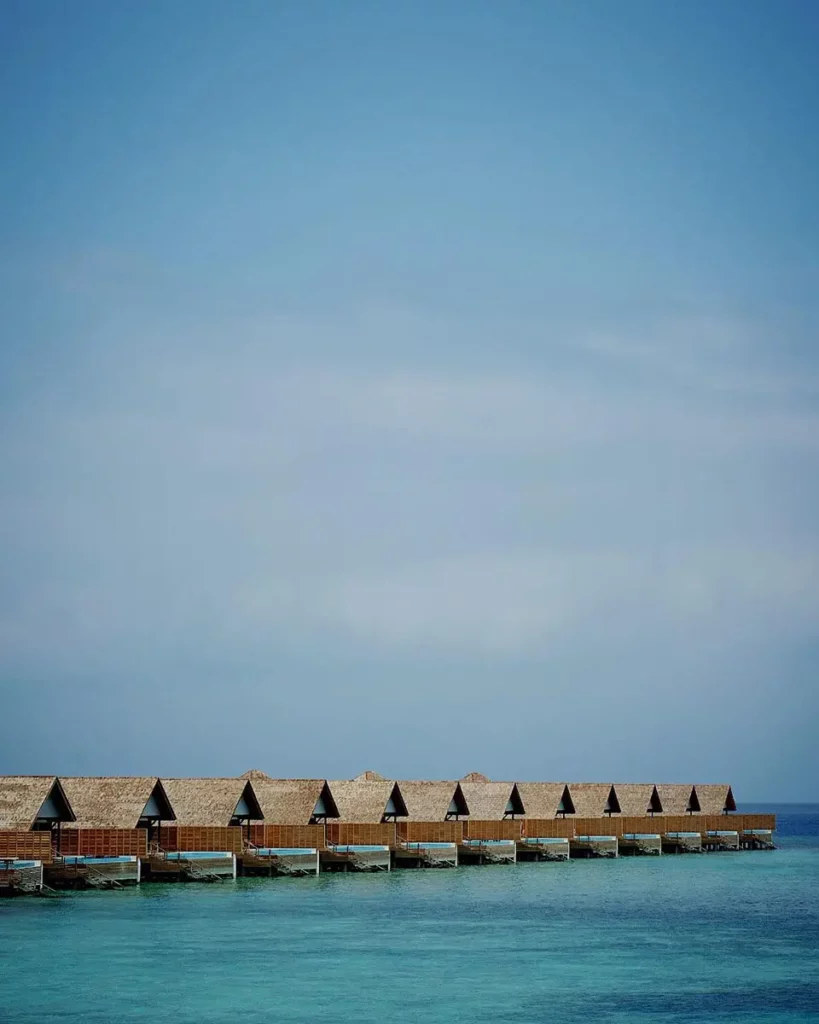 Vue verticale d'un alignement géométrique de Water Villas à Emerald Faarufushi, montrant la ligne de construction s'avançant dans le bleu de l'Océan Indien.
