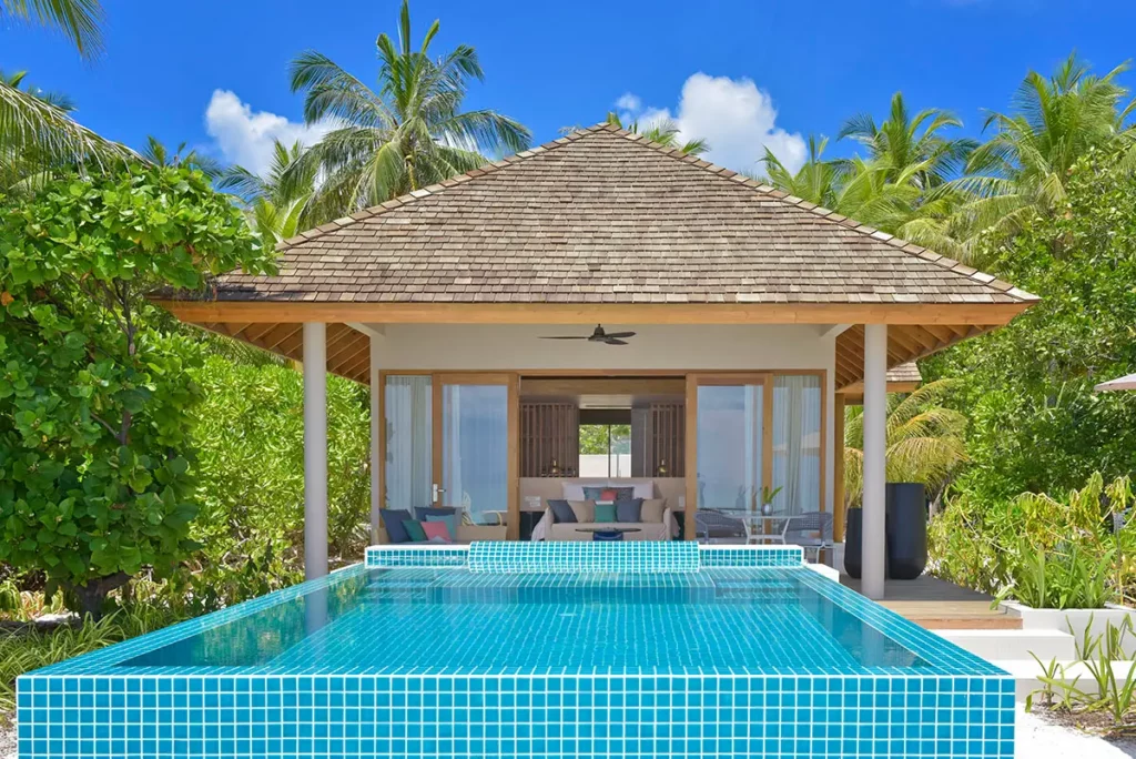 Vue depuis la plage d'une Beach Villa avec piscine privée à Emerald Faarufushi, nichée dans la végétation tropicale de l'atoll de Raa.