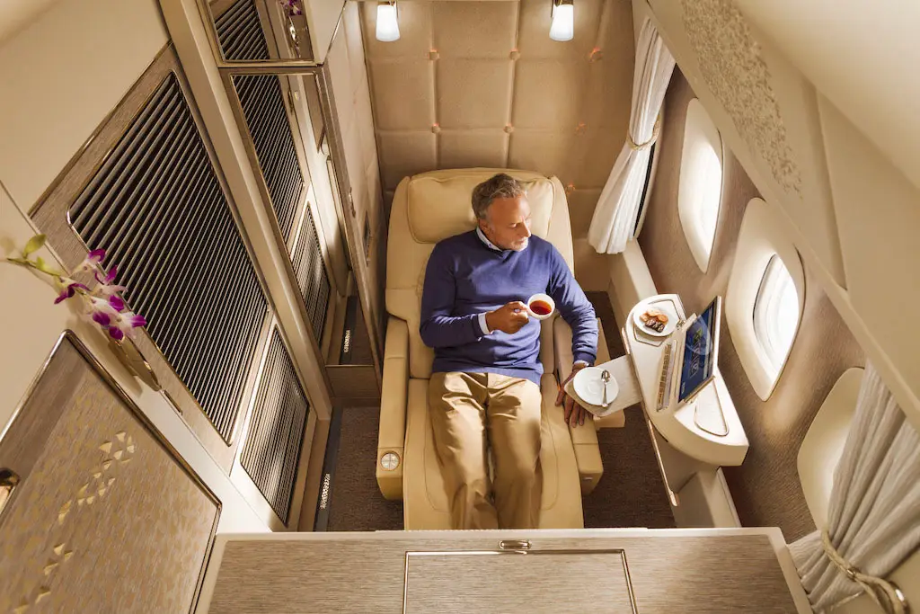 Vue intérieure d'une suite privée Emirates First Class avec le siège en position Zero Gravity et porte fermée.