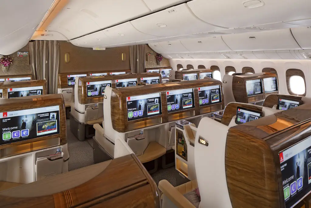 Cabine Classe Affaires Emirates vue de l'arrière montrant les larges écrans individuels et les finitions en bois d'acajou.