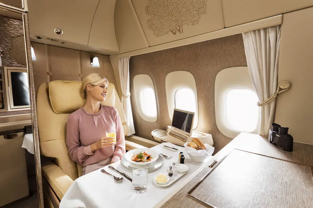 Service d'un repas gastronomique en Première Classe Emirates avec vue par le hublot à 33 000 pieds.