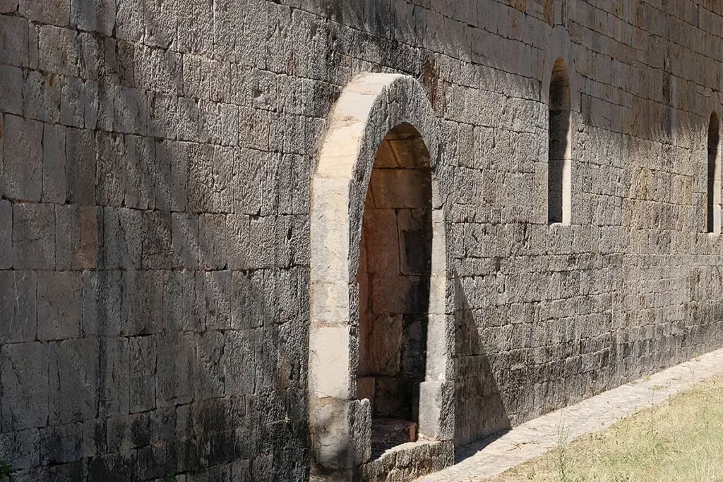 Détail architectural d'un enfeu dans le mur sud de l'abbatiale de l'Abbaye du Thoronet, montrant une niche funéraire en arche de pierre.