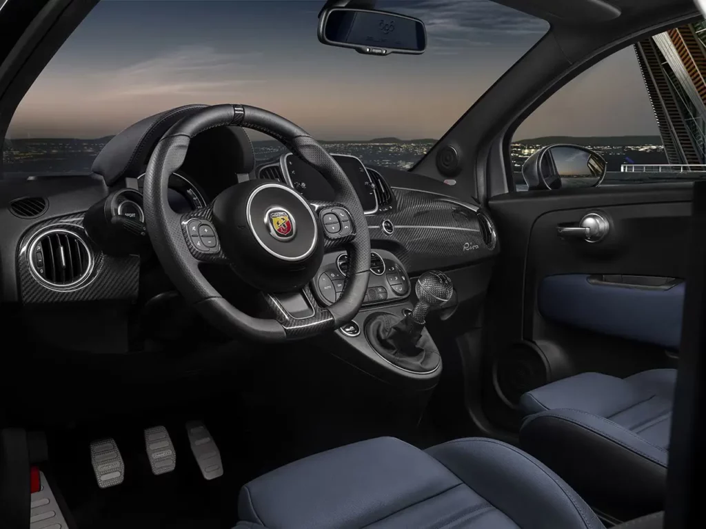 Vue intérieure côté conducteur de l'Abarth 695 Rivale montrant le tableau de bord en fibre de carbone et l'instrumentation sportive.