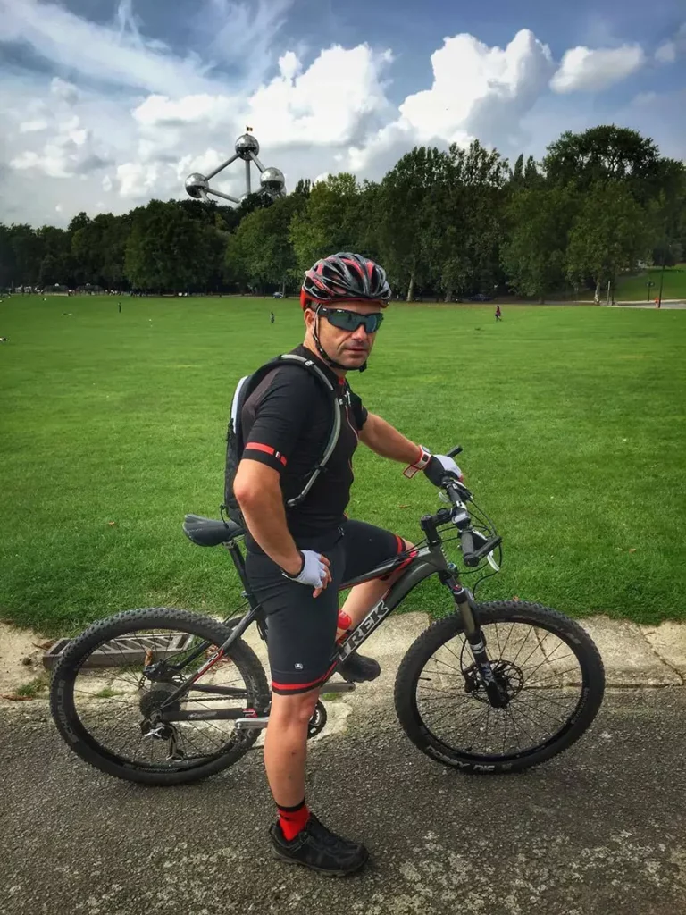 Le blogueur lifestyle voyage belge Michel Gronemberger pose avec son vélo au parc de Laeken, avec l'Atomium en arrière-plan.