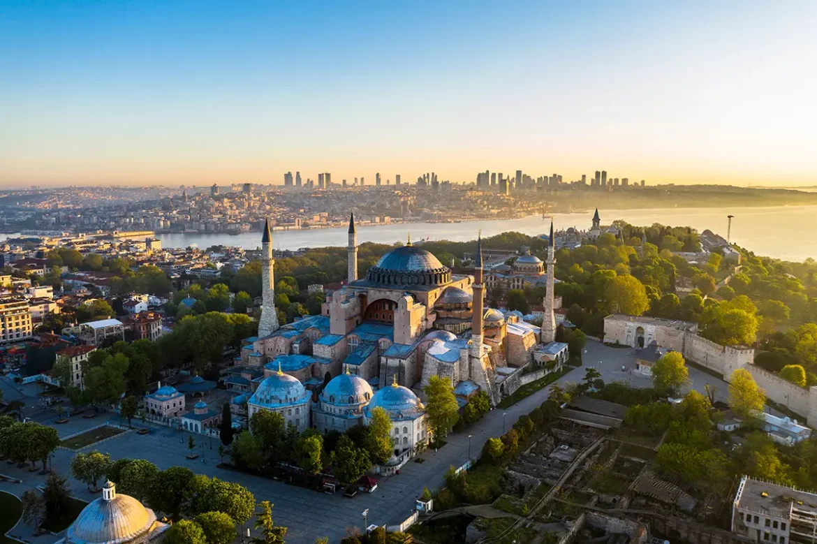Road-trip en Turquie, vue aérienne de la mosquée Sainte-Sophie à Istanbul, avec le détroit du Bosphore et les gratte-ciels modernes en arrière-plan.