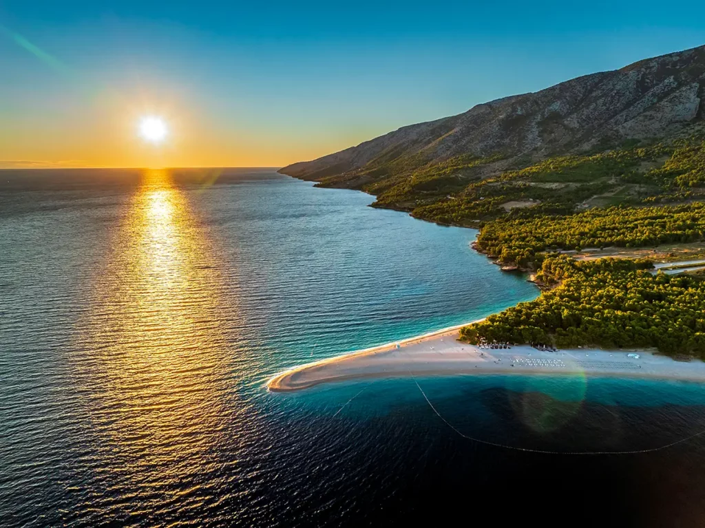 Vue aérienne de la célèbre plage de Zlatni Rat sur l'île de Brač au coucher du soleil, un symbole incontournable des îles croates.
