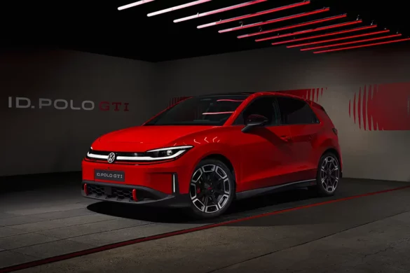 Vue de trois-quarts avant de la nouvelle Volkswagen ID. Polo GTI électrique rouge dans un garage au design futuriste avec phares allumés.