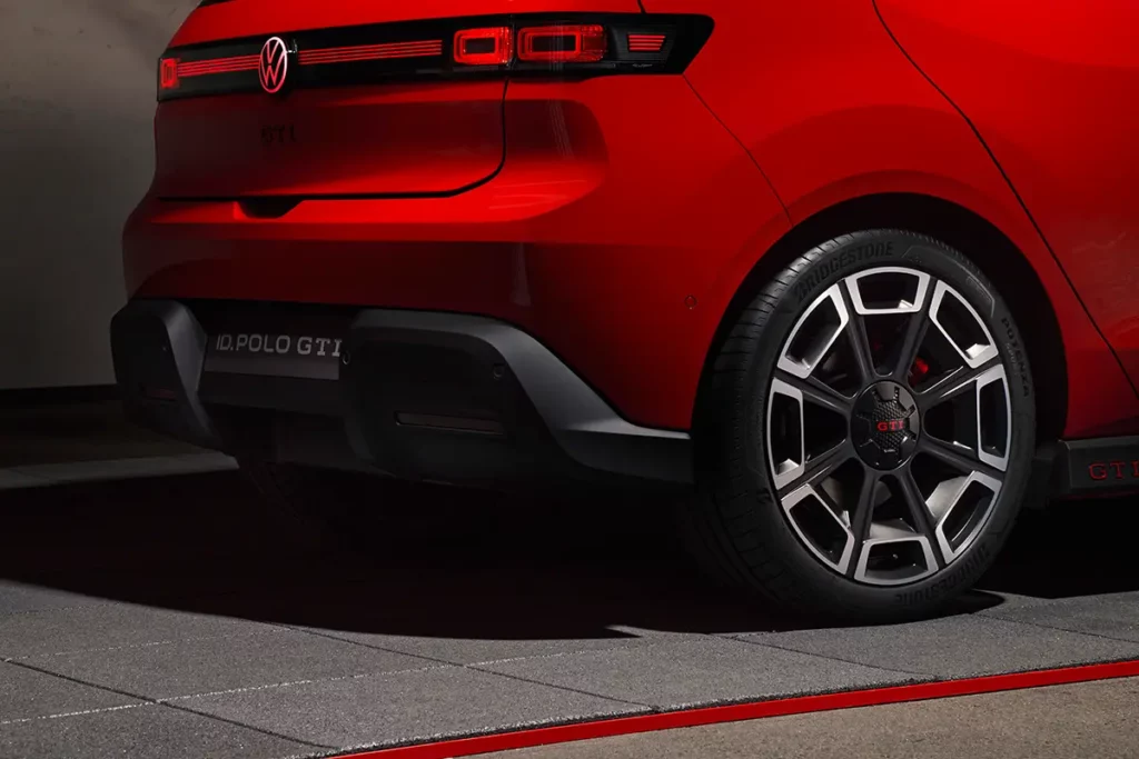 Gros plan de trois-quarts arrière sur le logo GTI sous le badge VW illuminé, la jante et le bas de caisse d'une Volkswagen ID. Polo GTI électrique rouge.