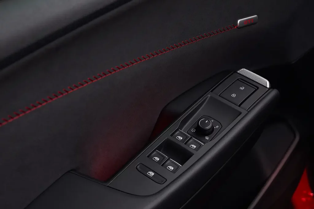 Gros plan sur le capitonnage intérieur d'une portière de Volkswagen ID. Polo GTI électrique avec coutures rouges, boutons de fenêtres et logo GTI.
