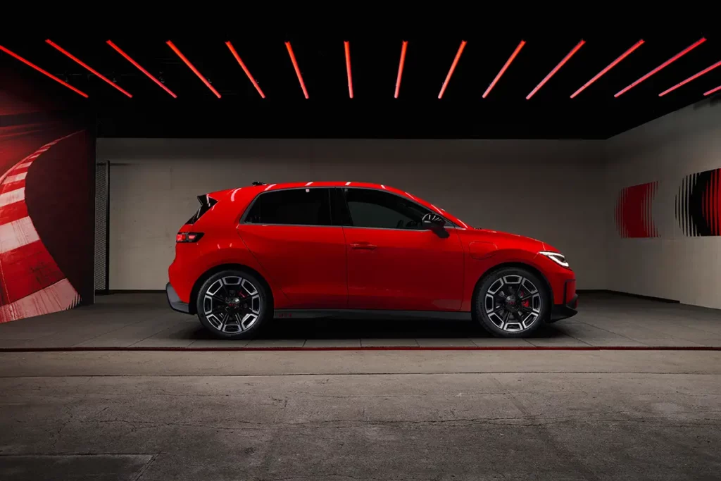 Vue complète de profil d'une Volkswagen ID. Polo GTI électrique rouge, montrant les lignes de la carrosserie, le bas de caisse marqué GTI et les jantes de 19 pouces.