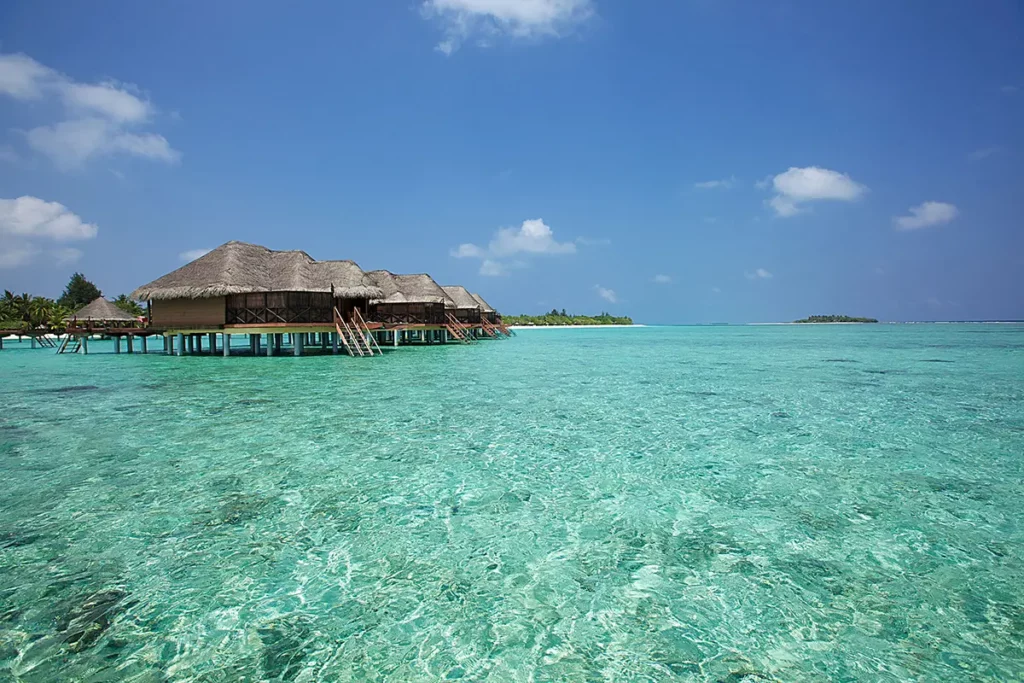 Vue depuis les eaux cristallines du lagon sur l'alignement des Water Villas sur pilotis du Six Senses Kanuhura.