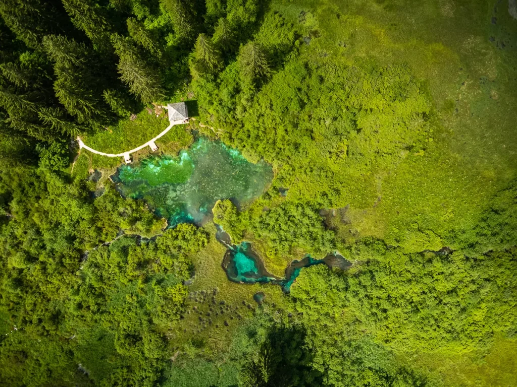 Vue aérienne graphique des passerelles en bois et d'un lac turquoise aux Lovrenška jezera lors d'un road-trip en Slovénie.