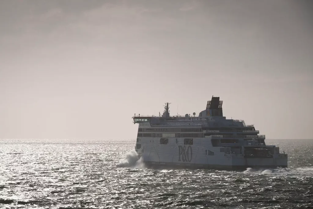 Le ferry Spirit of Britain de P&O Ferries à contre-jour sur la mer avec les reflets du soleil dans l'eau et les vagues.