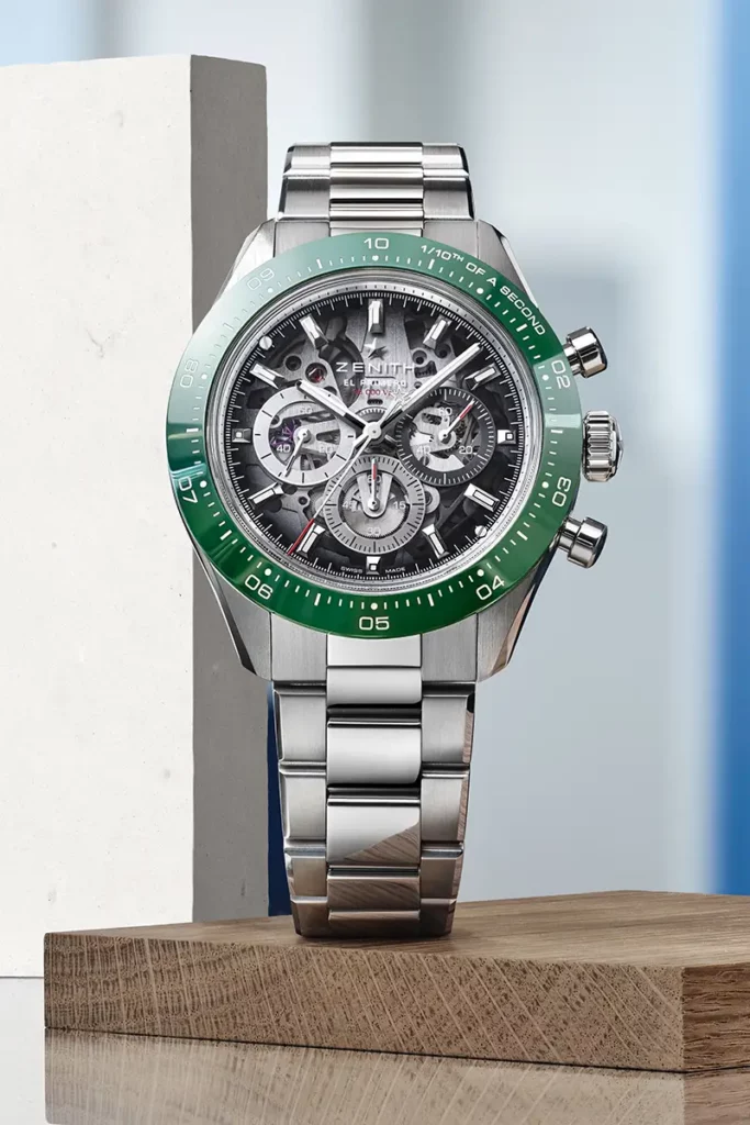 Chronographe Zenith Chronomaster Sport Skeleton en acier avec lunette en céramique verte posé de face sur une plaque de bois dans un atelier.