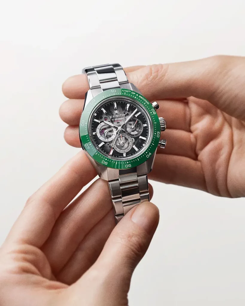 Montre Zenith Chronomaster Sport Skeleton en acier et lunette verte tenue à deux mains face à l'objectif.