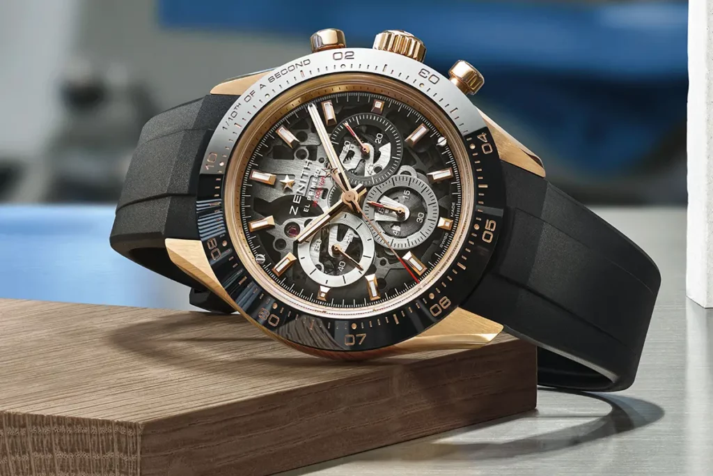 Montre Zenith Chronomaster Sport Skeleton en or rose couchée sur une fine plaque de bois et une surface métallique réfléchissante en atelier.