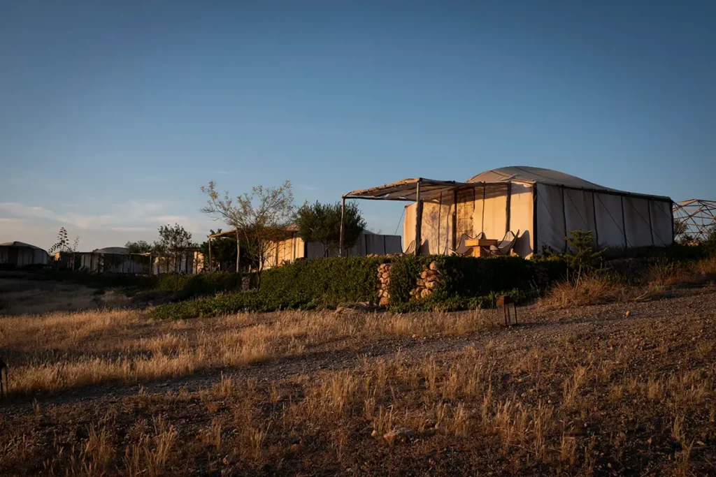 Enfilade de tentes lodge éclairées par la lumière dorée du soleil de fin de journée au domaine Terre des Étoiles dans le désert d'Agafay