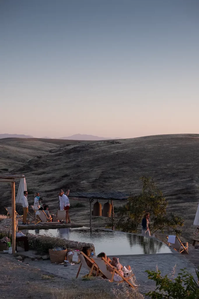 Touristes autour de la piscine de Terre des Étoiles admirant le coucher de soleil dans le désert d'Agafay