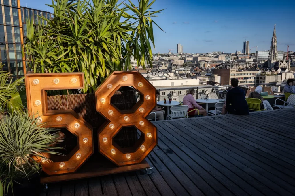 Le logo lumineux en bois du rooftop 58 à l'entrée de la terrasse est et vue sur Bruxelles