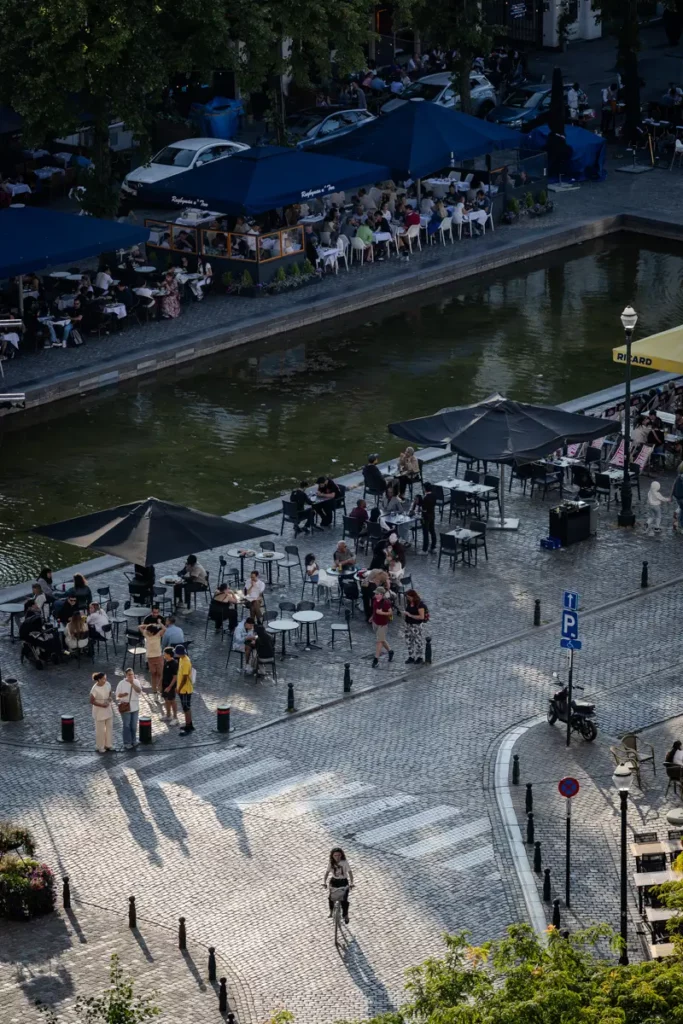 Zoom au téléobjectif depuis le rooftop 58 sur les terrasses de la place Sainte-Catherine et une cycliste dans la lumière du soir