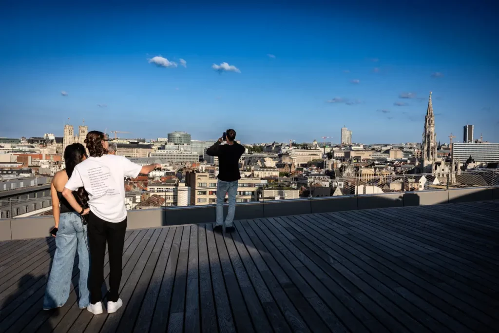 Trois personnes de dos admirant le panorama de Bruxelles depuis la terrasse est du rooftop 58