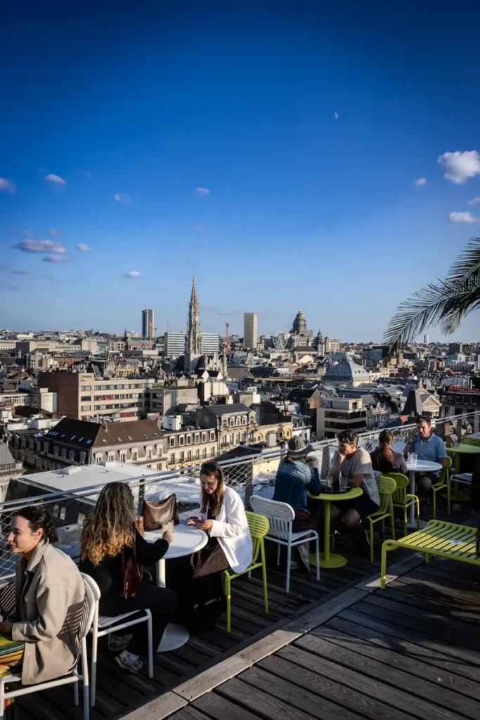 Enfilade de tables occupées sur la terrasse du rooftop 58 avec vue sur les toits de Bruxelles