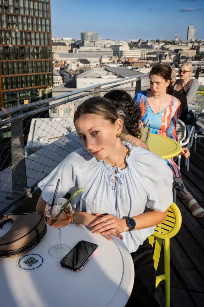 Une jeune femme détendue avec un cocktail sur le rooftop 58 à Bruxelles