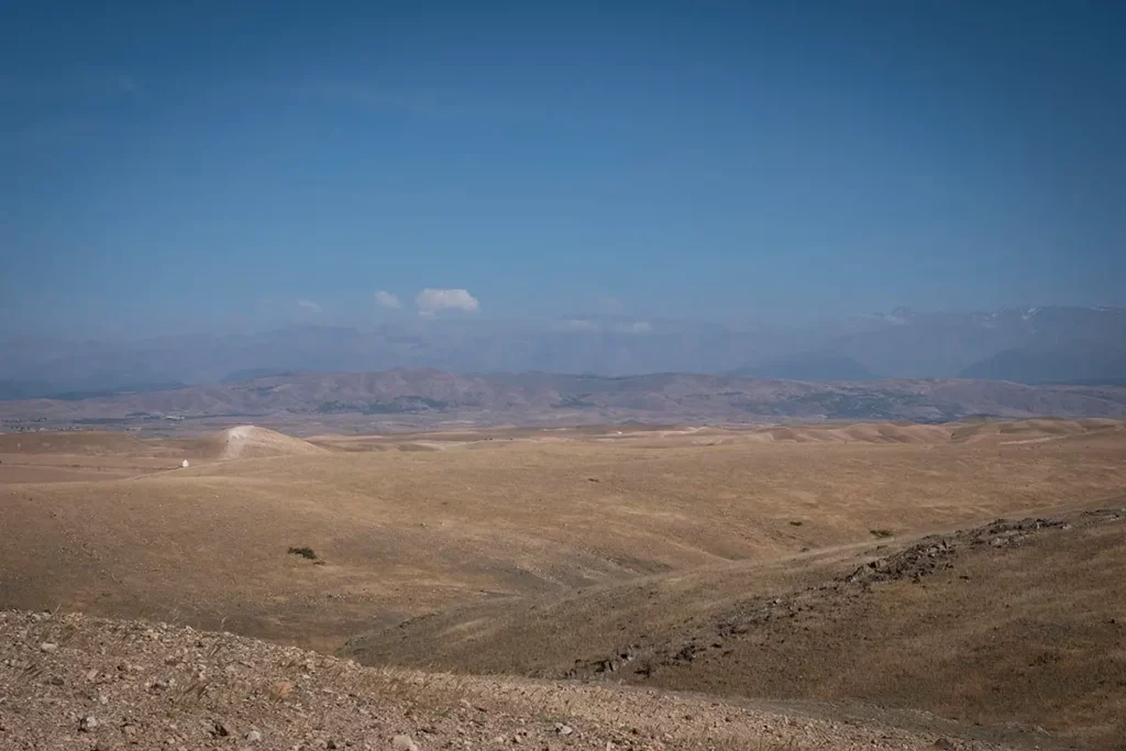 Vue panoramique sur les collines caillouteuses du désert d'Agafay et l'Atlas depuis le domaine Terre des Étoiles
