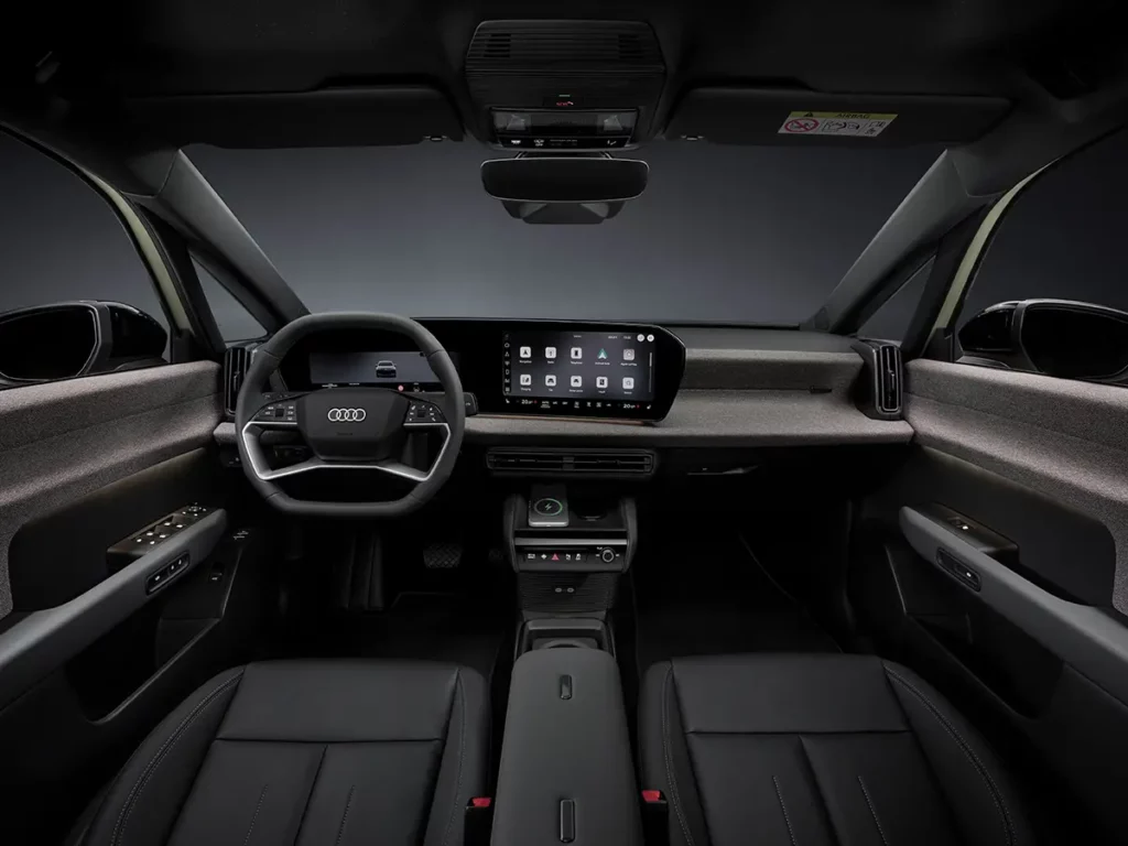 Vue de face de l'habitacle et du poste de conduite de l'Audi A2 e-tron, mettant en valeur le volant, le tableau de bord épuré et le double écran MMI