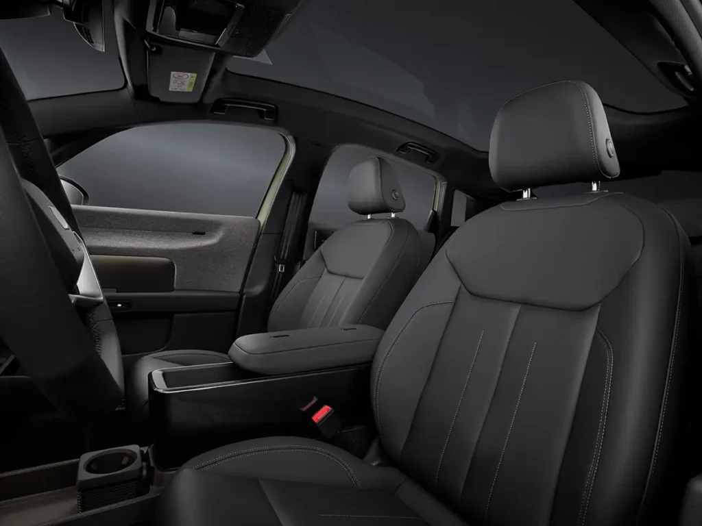 Vue intérieure de l'Audi A2 e-tron se concentrant sur les sièges avant gainés de cuir sombre et le grand toit vitré panoramique baignant l'habitacle de lumière