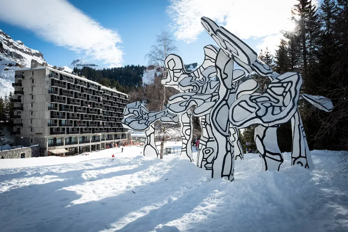 sculpture des hourloupes de jean dubuffet au premier plan avec un immeuble bauhaus et le cirque naturel de la station de flaine en arriere-plan